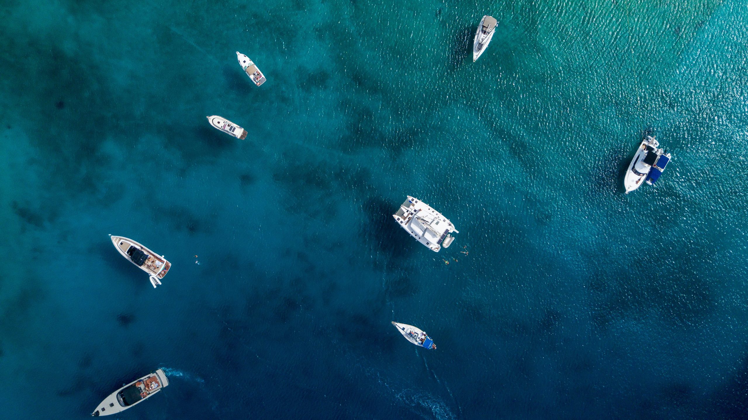 Photo Credits ©Magnific.com - Aerial view of yachts and leisure vessels at anchor in crystal-clear waters.